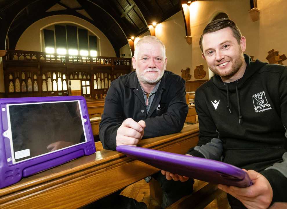 Two men looking to camera with iPads with purple frames.