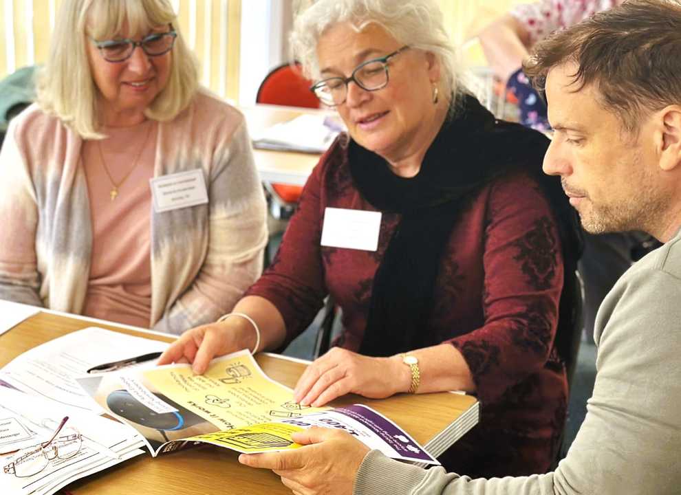Two women look at a BWBF leaflet with a member of staff