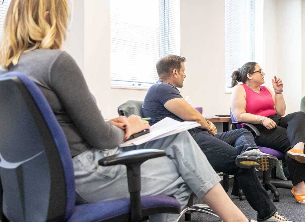 BWBF team members sit together in an office space discussing ideas at a team meeting