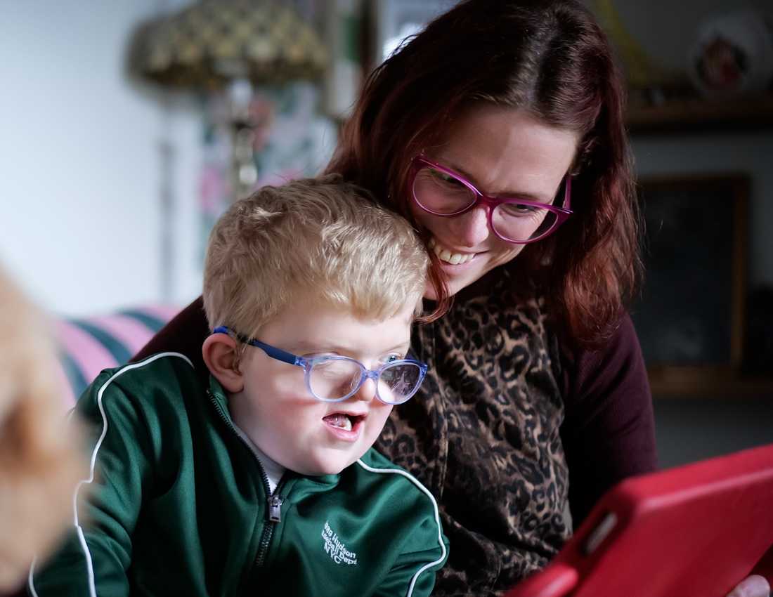 Lori beams down on her son Chip as they huddle comfortingly around his iPad from Visably.