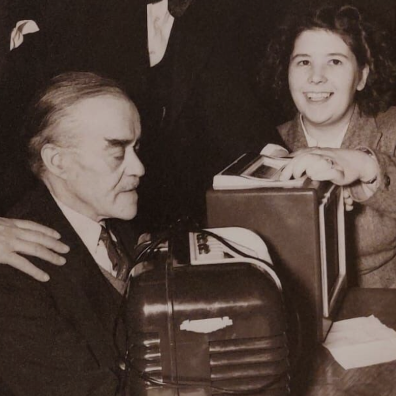 A black and white photo of people gathered around a Bush DAC10 radio, given to BWBF in the 1950s