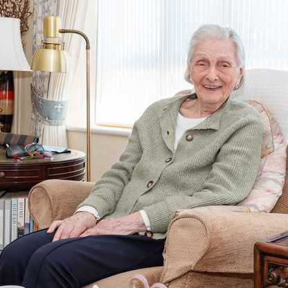 Doreen, who got a free Echo Dot from BWBF at the age of 95, smiles as she sits in an armchair with her device next to her