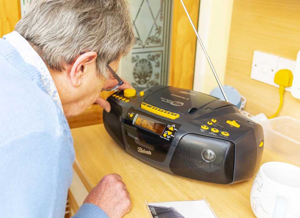 Older woman pressing buttons on a radio in a kitchen