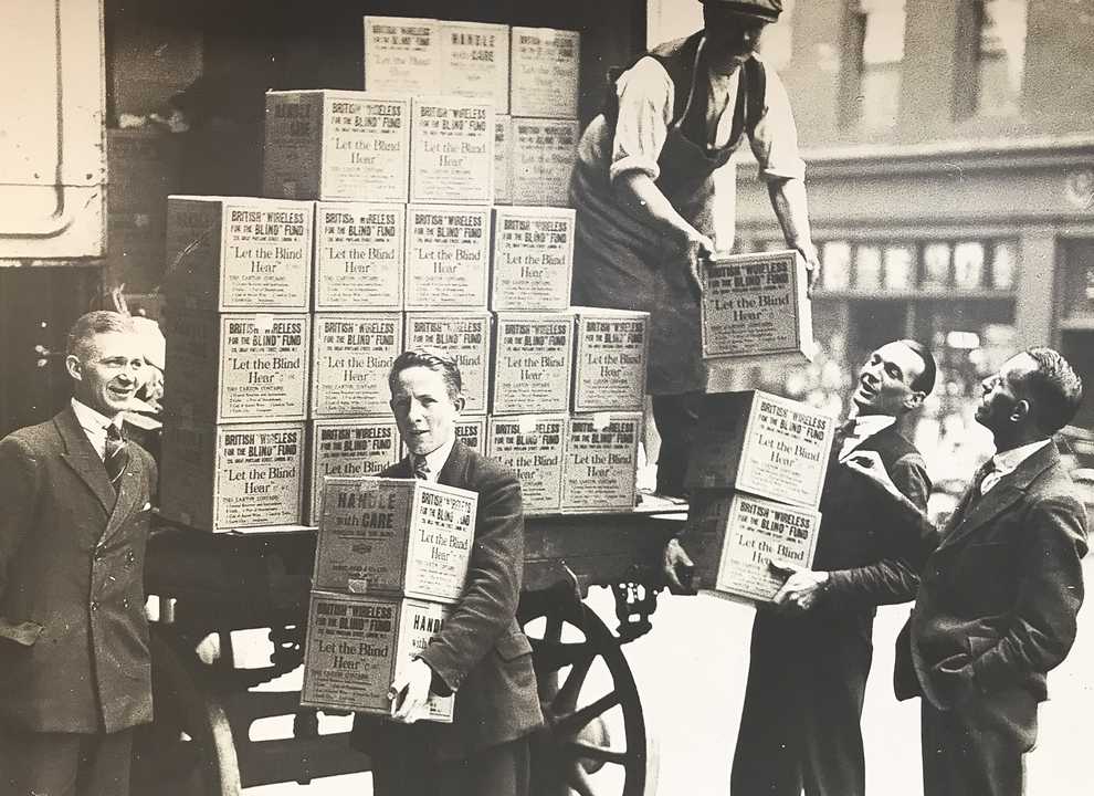 A sepia historical photo of young men unloading boxes labelled BWBF off a truck.